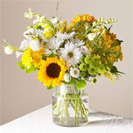 Bouquet of sunflowers, white daisies, and yellow flowers in a glass vase