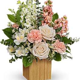 Pink and white floral arrangement in a wooden cube vase