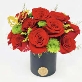 Red roses with green accents in a black cylindrical box