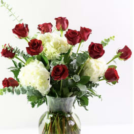Red roses and white hydrangeas in a clear glass vase