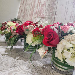 Three red and white floral centerpieces in striped glass vases