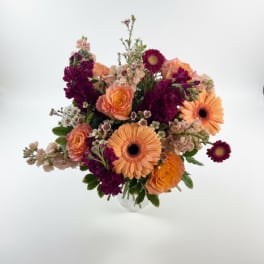 Mixed bouquet of orange roses and gerbera daisies in a clear vase