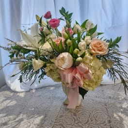 Mixed bouquet of pink and white flowers in a vase with a pink ribbon