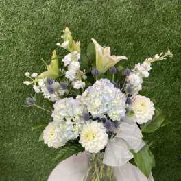 Bouquet of white and pale pink flowers in a glass vase with a sheer ribbon