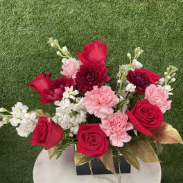 Red roses and pink carnations arranged in a black box