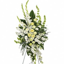 Standing floral spray with white and pale yellow flowers on a metal easel