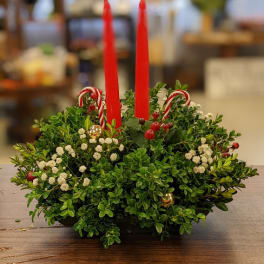 Holiday centerpiece with red candles, candy canes, and greenery