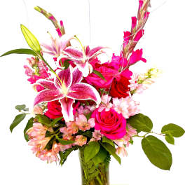 Pink lilies and roses arranged in a clear glass vase