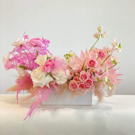 Pink and white floral arrangement in a white rectangular container
