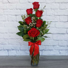Red roses arranged in a clear glass vase with a red ribbon