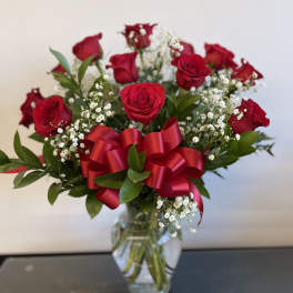 Red roses in a clear glass vase with a red ribbon bow