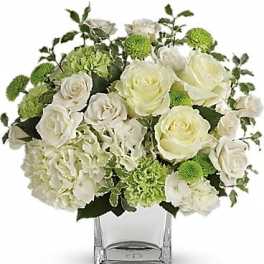White roses and green carnations arranged in a clear glass vase