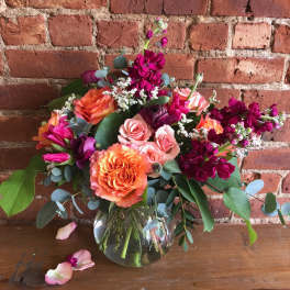 Bouquet of orange, pink, and magenta flowers in a glass vase