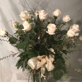 White roses in a clear glass vase with a gold ribbon bow
