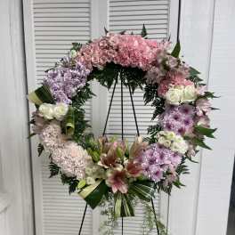 Large pink and white floral wreath on a black stand
