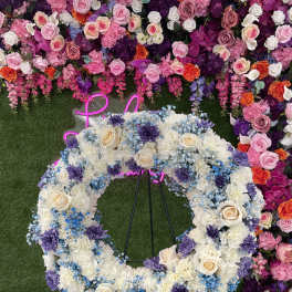 Large floral wreath of white, blue, and purple flowers on a stand