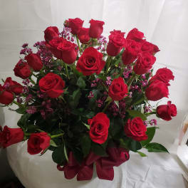 Bouquet of red roses with small pink filler flowers and a burgundy ribbon