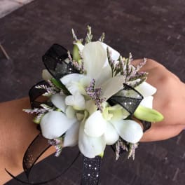 White orchid corsage with black ribbon on a wrist