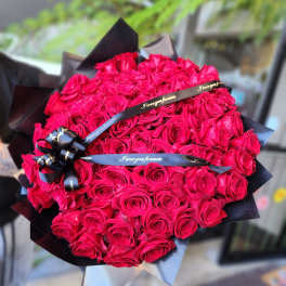 Large bouquet of hot pink roses wrapped in black paper with ribbon