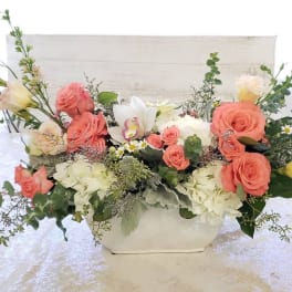 Coral roses and white hydrangeas in a white rectangular vase