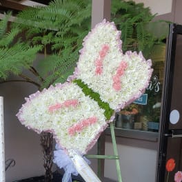 Heart-shaped standing floral tribute with white and pink flowers on an easel