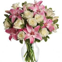 Pink lilies and white roses arranged in a clear glass vase.