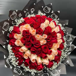 Round bouquet of red and peach roses with white filler wrapped in black printed paper