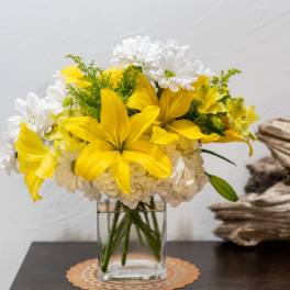 Yellow lilies and white daisies in a clear glass vase