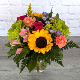 Colorful mixed bouquet with a sunflower in a glass vase