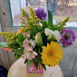 Mixed bouquet in a pink vase with yellow, purple, pink, and white flowers