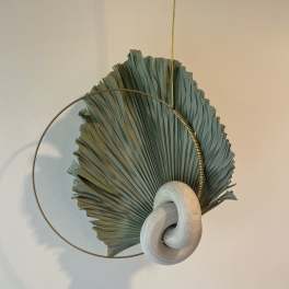 Abstract wall hanging with a dried fan-shaped leaf and circular metal ring