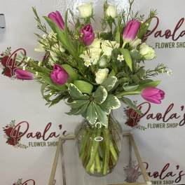 Pink and white tulips with white roses in a glass vase