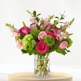 Pink roses and lilies arranged in a clear glass vase