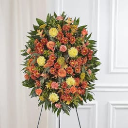 Standing floral wreath with orange and yellow blooms on an easel
