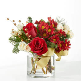 Red roses and red daisies in a clear glass vase with gold ribbon