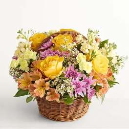 Basket of yellow roses and pink daisies with peach flowers