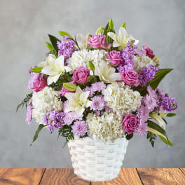 Pink roses and white lilies in a white woven basket