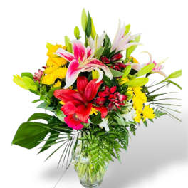 Mixed bouquet of lilies, roses, and yellow daisies in a glass vase