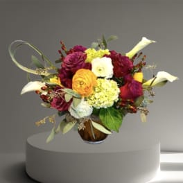 Mixed bouquet with calla lilies, roses, and hydrangeas in a glass vase