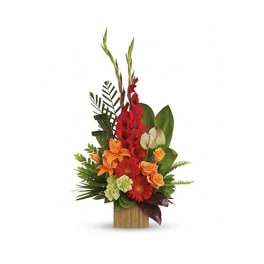 Tall tropical arrangement with red, orange, and green flowers in a wooden container