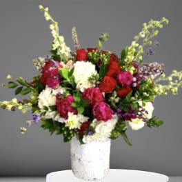Mixed bouquet of red, pink, and white flowers in a white vase