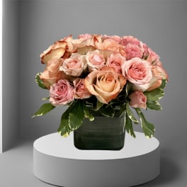 Pink and peach roses arranged in a dark green vase