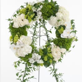 White and green floral wreath on a stand with orchids and roses