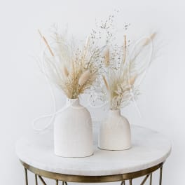 Two white ceramic vases with dried grasses and beige stems