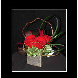 Red roses in a square vase with looping decorative reeds