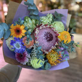 Mixed bouquet with colorful flowers wrapped in purple paper
