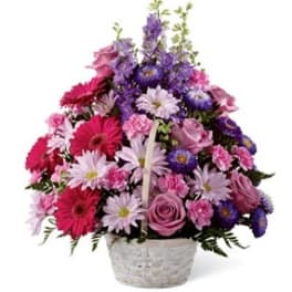 Mixed pink and purple flowers arranged in a white basket