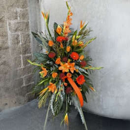 Tall orange floral standing spray with tropical blooms and ribbon