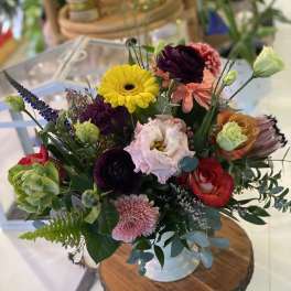 Mixed bouquet in a white vase with bright yellow, pink, red, and purple blooms