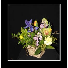 Mixed floral arrangement in a rectangular basket with purple and yellow blooms
